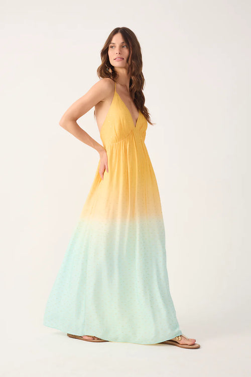 Woman wearing a yellow to light blue gradient maxi dress on a white background