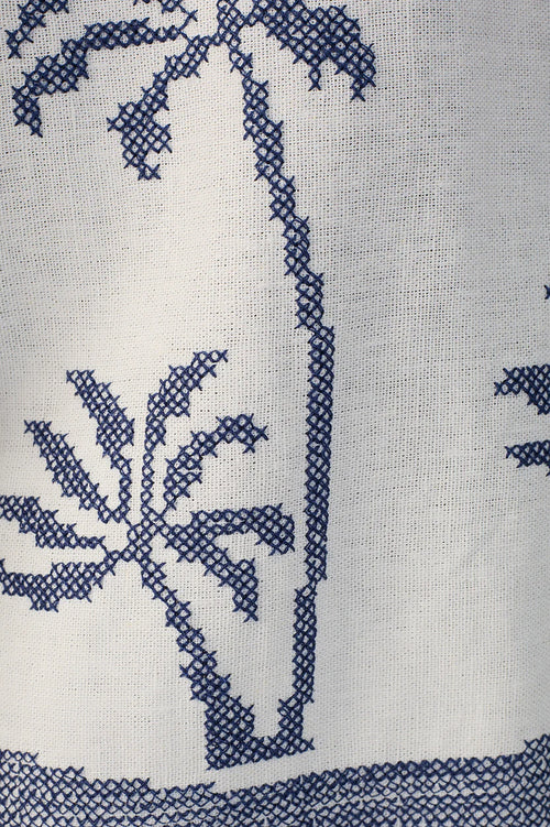 blue stitched palm tree pattern on white linen fabric.