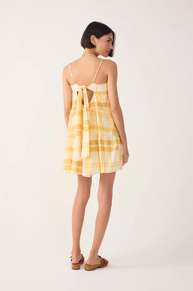 Ba view of a woman wearing a yellow checkered dress with brown sandals against a white backgroundk