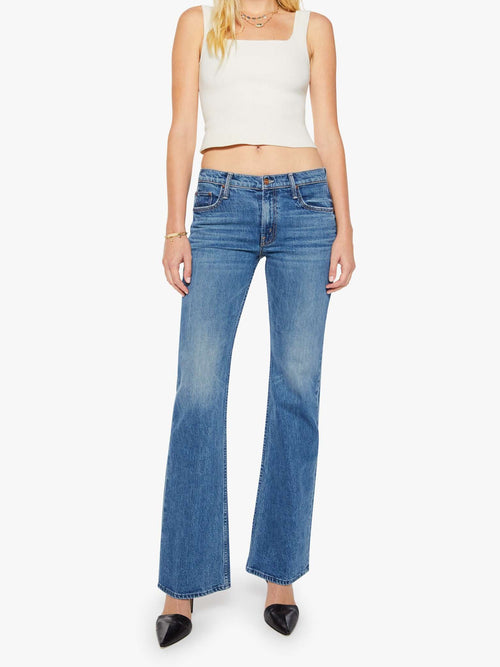 Woman wearing blue jeans and a white top on a white background