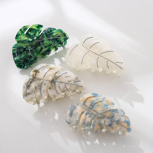 Four leaf-shaped hair clips in green, white, and multicolor on a light background