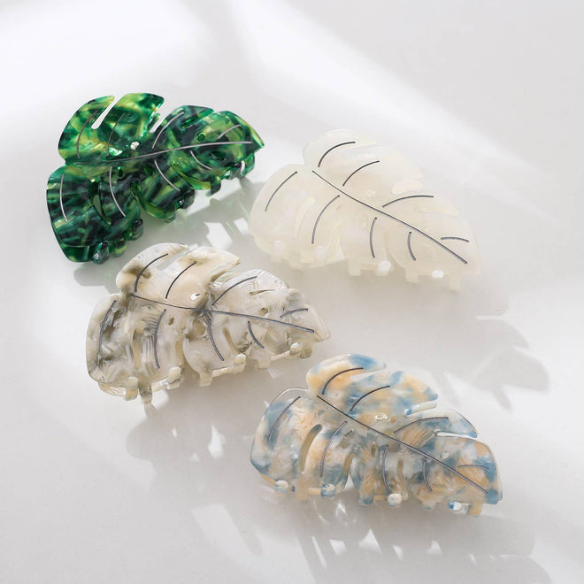 Four leaf-shaped hair clips in green, white, and multicolor on a light background