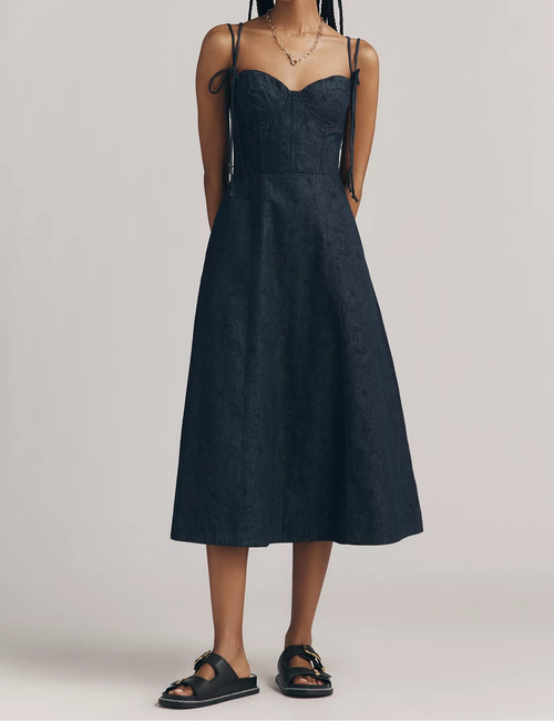 Woman wearing a dark blue dress against a plain background