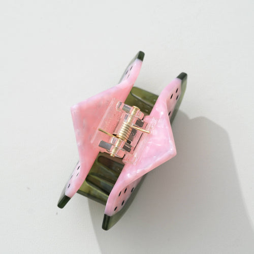 Watermelon hair clip with pink flesh and black seeds and green rim on a white background