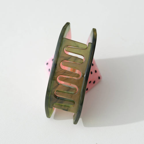 Watermelon hair clip with pink flesh and black seeds and green rim on a white background