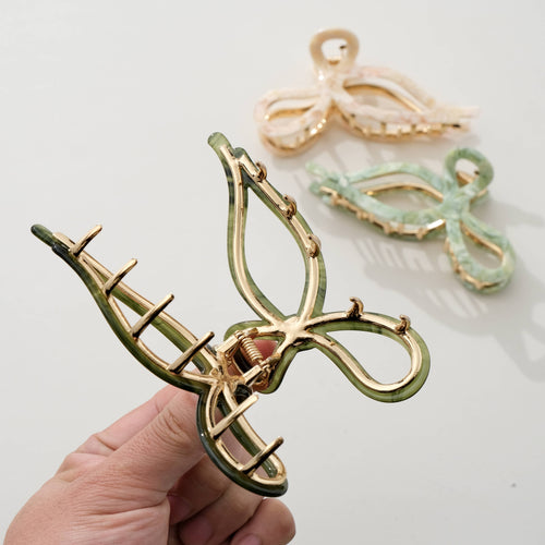 Three bow shaped hair clips in green, beige, and olive green on a light background