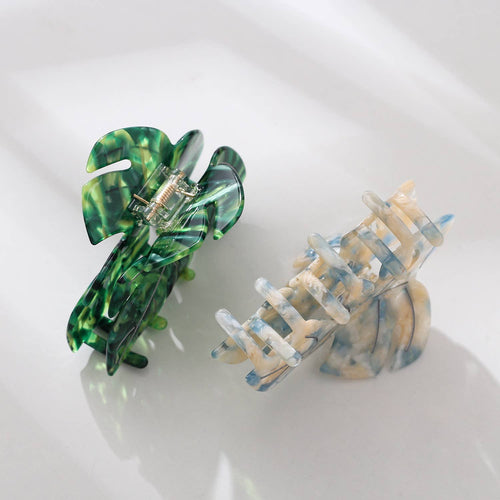 Two hair clips, one green and one multicolored, on a white background