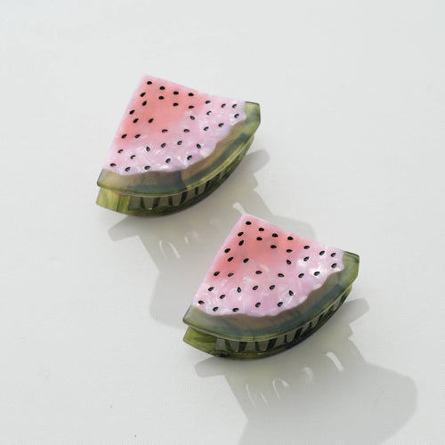 Two watermelon hair clips with pink flesh and black seeds and green rim on a white background