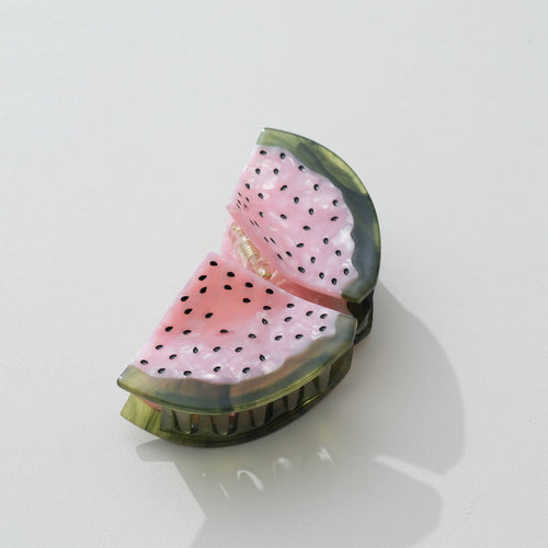 Two watermelon hair clips with pink flesh and black seeds and green rim on a white background