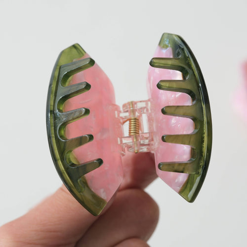 Watermelon hair clip with pink flesh and and green rim on a white background
