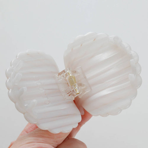 A shell-shaped white hair clip on a white background