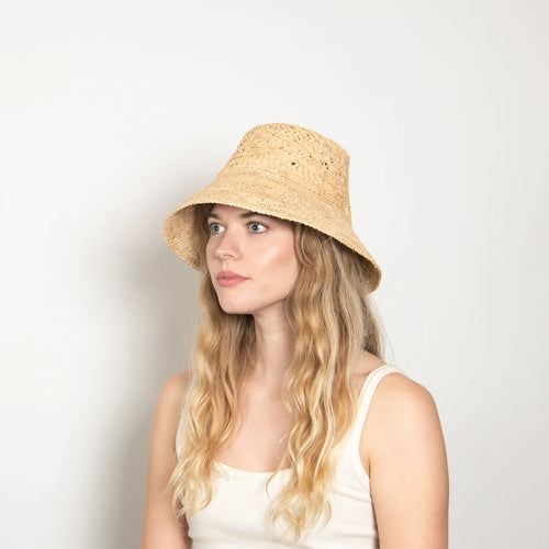 Woman wearing a straw hat against a plain background