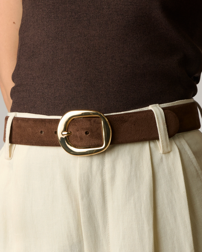 Brown belt with gold buckle worn by a person in a brown shirt and beige pants.