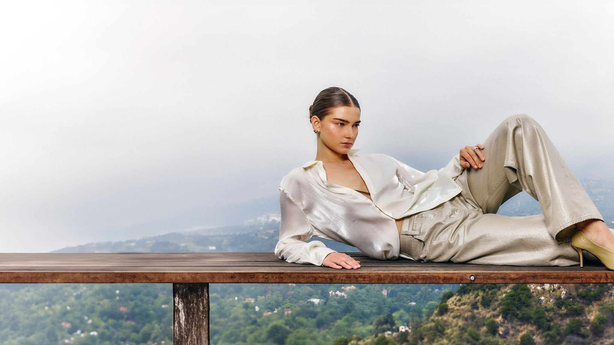 Woman sitting on a wooden railing with a scenic background