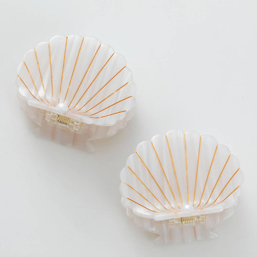 Two shell-shaped hair clips with gold lines on a white background