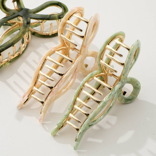 Three bow shaped hair clips in green, beige, and olive green on a light background